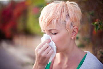 Woman with with allergy symptom blowing nose. People, health care and medical concept