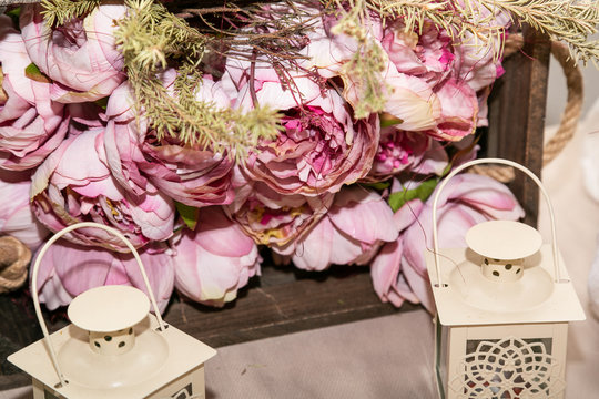 Candiles blancos a los lados y flores rosas de fondo 