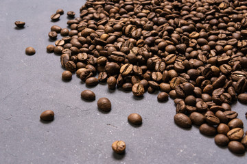 Roasted coffee beans in bulk on a gray concrete background. dark cofee roasted grain flavor aroma cafe, natural coffe shop background, top view from above, copy space