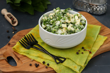 Salad with ramson wild garlic, eggs and mayonnaise in a white bowl