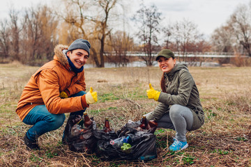 Couple of volunteers cleaned up the trash in park. People picked up garbage and showing result with...
