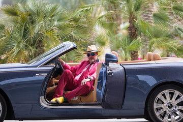 a rich businessman driving a cabriolet