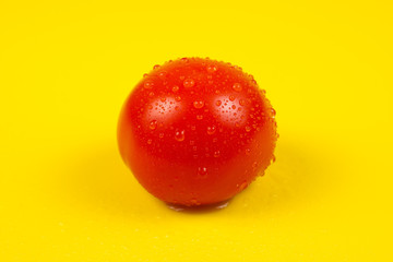 Fresh red tomato isolated on yellow background.