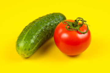 Beautiful fresh cucumber and tomato on yellow background. Ripe vegetables