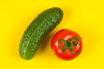 Beautiful fresh cucumber and tomato on yellow background. Ripe vegetables