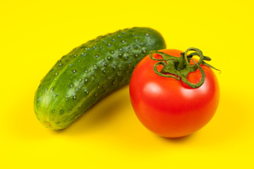 Beautiful fresh cucumber and tomato on yellow background. Ripe vegetables
