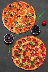 Pepperoni Pizza and Pizza with Mozzarella cheese, Tomatoes, pepper, olive, Spices and Fresh arugula. Pizza Margherita or Margarita on Dark grey black slate background