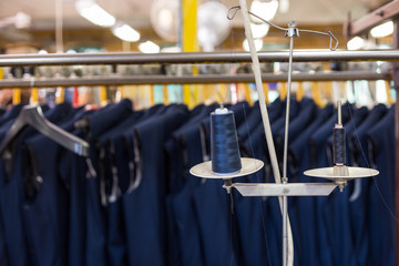 Detail close up shot of garment production line. Spool with dark blue thread at stitching station.