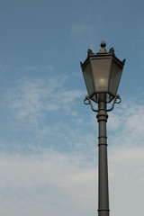 Fototapeta na wymiar Street lamp against a blue sky with clouds