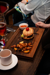 Delicious burger with beef patty, bacon, cheese and cabbage on rustic wooden background served in a bar