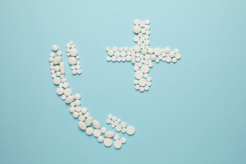 Telephone receiver and cross of pills on blue background. Call doctor, the concept of medical care.