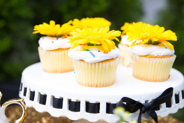 Yellow cupcakes with sprinkles and flowers on a cakestand 