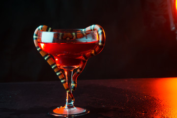transparent glass with a snake against a dark background. close up. liquid in a glass
