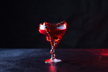 beautiful transparent glass with red liquid and little snake which was curtailed in the form of heart against a dark background