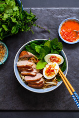 Vietnamese pho with duck with crispy skin, bean sprouts and egg, chili sauce and herbs