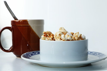 A cup of coffee and a plate of popcorn on a white background, a great start to the working day.