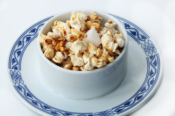 Plate with popcorn on a white background, a great start to the working day, delicious dessert for a good mood