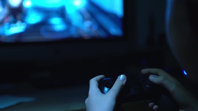 4K footage of boy playing video games sitting in darkness using joystick
