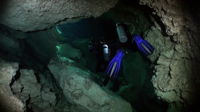Divers in cave in underground water of underwater Yucatan Mexico cenotes. Dangerous extreme diving in clean and clear water.