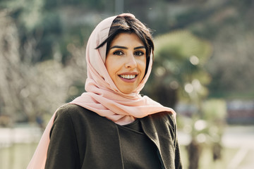 Beautiful young Muslim woman in park smiling at camera