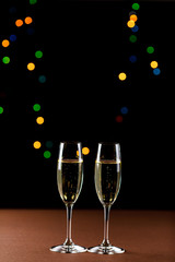 glasses of champagne on black  background with bokeh circles. Place for text.