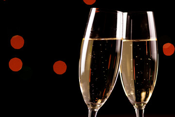 glasses of champagne on black  background with bokeh circles. Place for text.