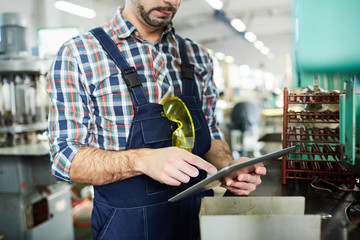 Mid section portrait of unrecognizable factory worker using digital tablet while operating machine units in workshop, copy space