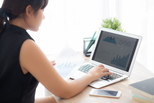 Beautiful asian woman working and typing with laptop computer at office, businesswoman looking graph diagram analysis statistic data of finance, girl using notebook, profit growth, business concept.