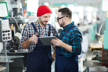 Portrait of two factory workers using digital tablet in workshop