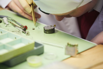 Closeup of unrecognizable man assembling intricate  mechanical watch, copy space