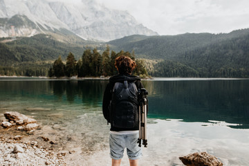 Tourist Fotograf auf Reise von hinten an einem schönen See mit Ausblick auf die Berge, Alpen und den Wald