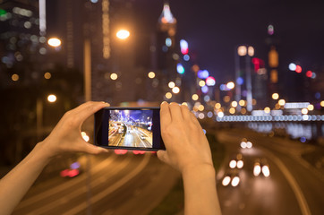 Hands using smartphone taking photo at night in Hong Kong