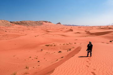 Fototapeta na wymiar A photographer standing in the sand dune in the arabian desert
