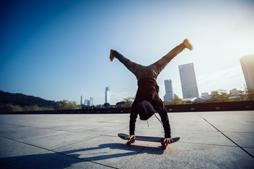 female skateboarder doing a handstand on skateboard in city © lzf
