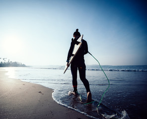 Woman surfer with surfboard ready to surf on a beach