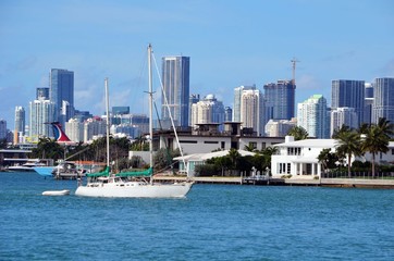 Sailboat cruising on auxiliary power on the Florida Intra-Coastal Waterway against a background of Miami  tall buildings skyline