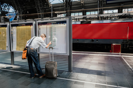 Pendler - Person auf der Reise am Gleis am Bahnhof unf schaut nach Informationen, weil der Zug Versp&auml;tung hat