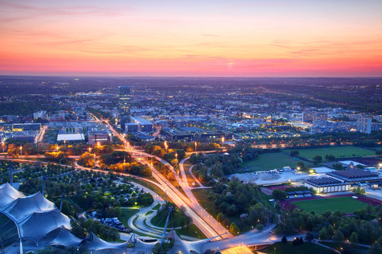 Modern European aerial cityscape in blue hour at dusk; commercial office buildings, highway junction, overpass, sports fields and high tower blocks in outskirts, Moosach Milbertshofen Munchen Germany