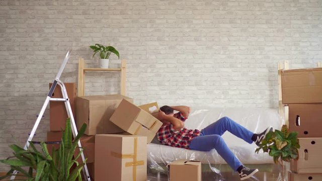 Man with large boxes in his hands falls on the sofa