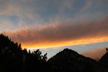 Silhouette of mountain and trees with colorful sunset in background