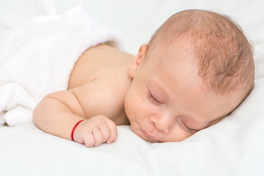 picture of a newborn baby curled up sleeping on a blanket