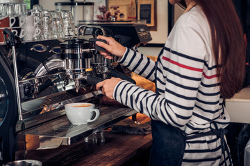 Asian barista woman making coffee cappuccino at cafe with machine at counter bar in eatery,Food and drink service concept