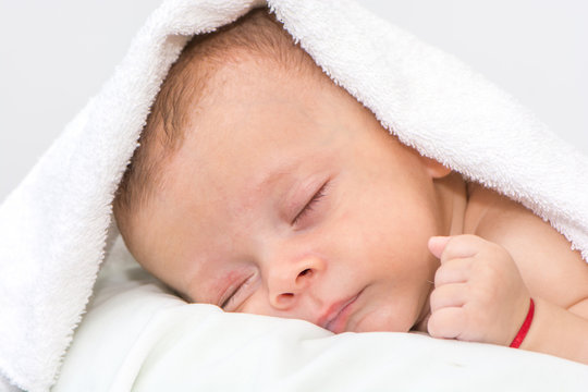 picture of a newborn baby curled up sleeping on a blanket