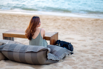 A beautiful asian woman enjoy sitting on the beach by the seashore