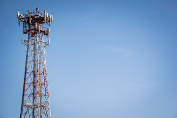 A metal cellular communications tower set on a clear blue sky background.