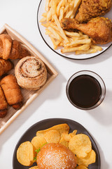 Freshly baked buns, big hamburger, fried crispy chicken and french fries on white table - Unhealthy food concept