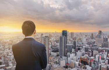 Fototapeta na wymiar Businessman with Osaka city in Japan at sunset. Business concept