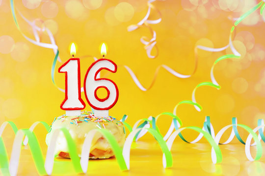 Sixteen years birthday. Cupcake with burning candles in the form of number 16. Bright yellow background with copy space