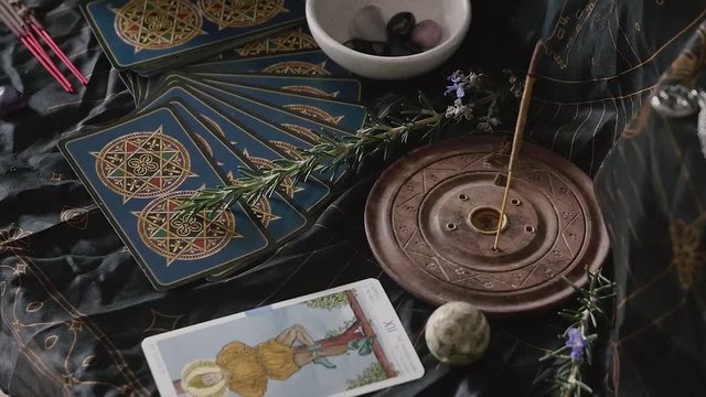 Placing tarot card on altar with incense, crystals and rosemary