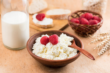 Fototapeta na wymiar Tvorog in rustic bowl, milk bottle, bread, berries and ears of golden wheat on wooden table